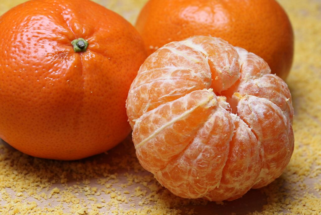 Close-up of fresh clementines and a peeled segment on a textured background.